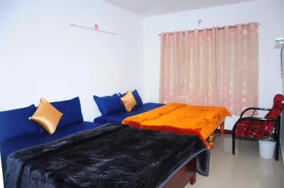 a living room with a blue couch with an orange blanket at A L Residency in Ooty