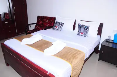 two twin beds in a room with a chair at A L Residency in Ooty