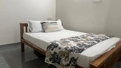 a bed with a black and white blanket and pillows at Johnnys Destination in Angamali