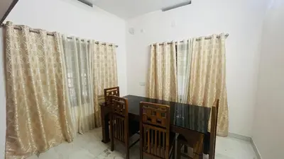 a dining room with curtains and a table and chairs at Johnnys Destination in Angamali