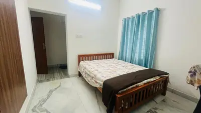 a bedroom with a bed and a blue curtain at Johnnys Destination in Angamali