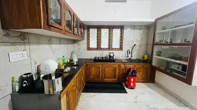 a kitchen with wooden cabinets and a red appliance at Johnnys Destination in Angamali