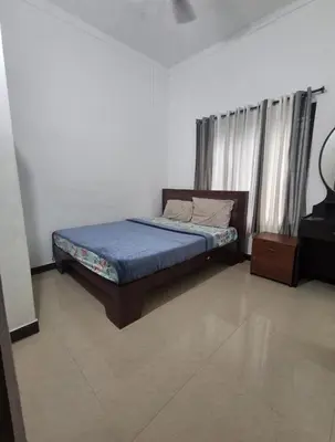 a bedroom with a bed with a blue comforter at Winter Valley Homestay in Vythiri