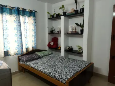 a bed in a room with shelves with plants at WooLiv in Coimbatore