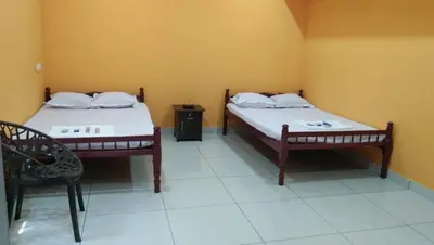two beds in a room with a table and a chair at Charis Guest house near Guruvayur, Kunnamkulam in Kunnamkulam