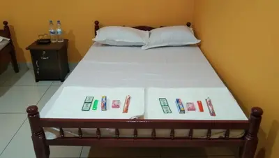 a bed with white sheets and remote controls on it at Charis Guest house near Guruvayur, Kunnamkulam in Kunnamkulam