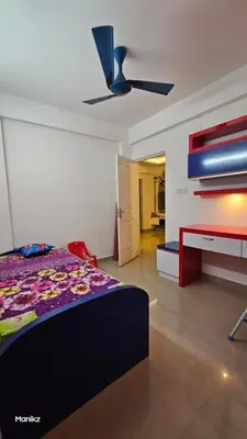a bedroom with a bed and a ceiling fan at Kulipini Family Apartment in Irinjālakuda