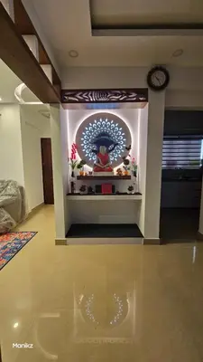 a living room with a clock on the wall at Kulipini Family Apartment in Irinjālakuda