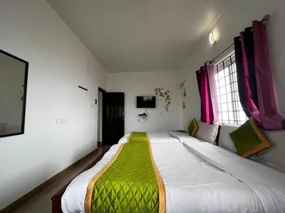 a bedroom with a large bed with a green blanket at Hideaway Home43 in Ooty