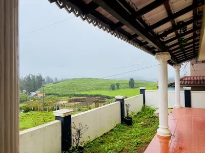 a porch with a view of a field and a hill at Teyt Castle - Ooty - Nilgiris in Ooty