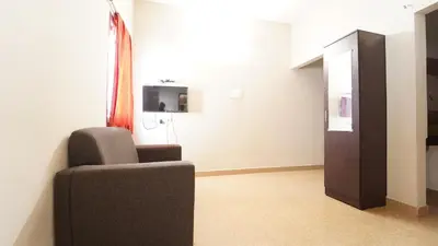a living room with a chair and a television at Airport Home Stay in Coimbatore