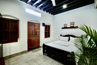 a bedroom with a bed and a wooden door at Idanazhi the corridor in Kozhikode