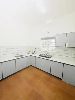 a large kitchen with white counters and white cabinets at Paradise Premium Villa Munnar in Munnar