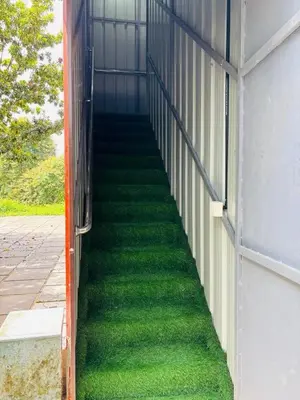 a stairway with green grass on the side of a building at whisperingstrem's RIVER view homestay in Padinjarathara