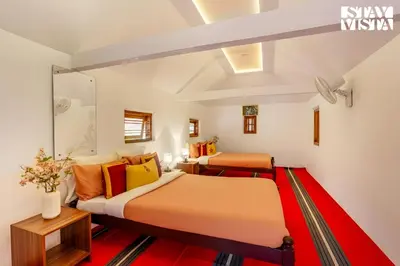 two beds in a room with orange and yellow pillows at StayVista at The River Mist with complimentary Breakfast & Bonfire in Wayanad