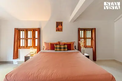 a bedroom with a large orange bed with two windows at StayVista at The River Mist with complimentary Breakfast & Bonfire in Wayanad