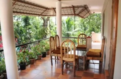 a dining room with a table and chairs on a balcony at Cozy Coffee Estate Homestay Coorg Madikeri in Madikeri