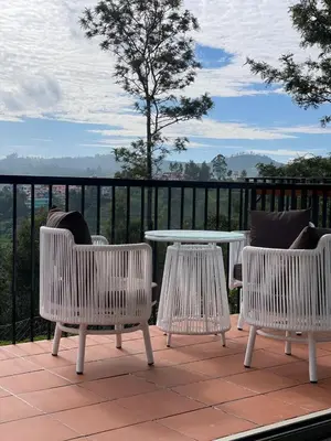 a patio with three chairs and a table on a balcony at Ozone The Misty Villa - Hill View in Coonoor