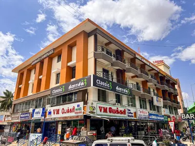 a large building with cars parked in front of it at Shri Amman Residency in Dhārāpuram