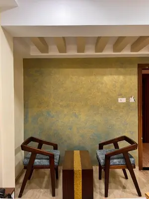 two chairs and a table in front of a wall at Shri Amman Residency in Dhārāpuram