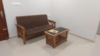 a brown couch and a table in a room at Lavender Airport suite in Nedumbassery