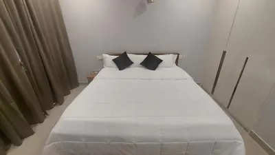a white bed with black pillows in a room at Lavender Airport suite in Nedumbassery