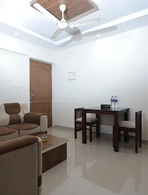 a living room with a ceiling fan and a table at Lavender Airport suite in Nedumbassery