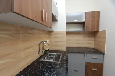 a kitchen with wooden cabinets and a sink at Lavender Airport suite in Nedumbassery