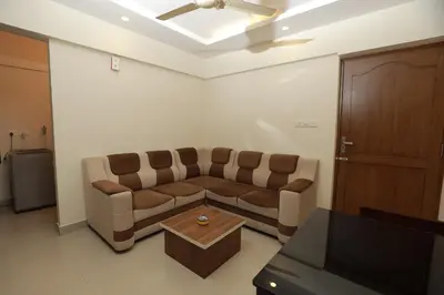 a living room with a couch and a table at Lavender Airport suite in Nedumbassery