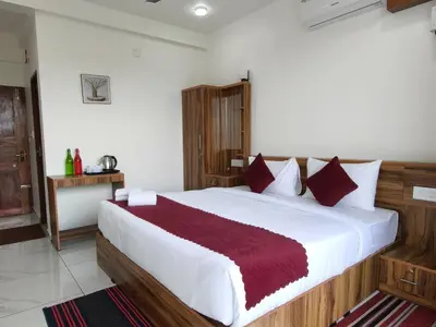 a bedroom with a large white bed with red pillows at Nirvanica Retreat Wayanad in Padinjarathara