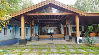 a large wooden pavilion with a bench on a patio at Grace Backwater Villa Coorg in Suntikoppa