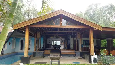 a pavilion with a bench and a chair on a house at Grace Backwater Villa Coorg in Suntikoppa