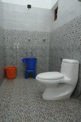 a bathroom with a toilet and a blue bucket at Willy's Home Stay in Parūr