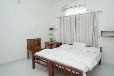 a bedroom with a bed and a table and a window at Willy's Home Stay in Parūr