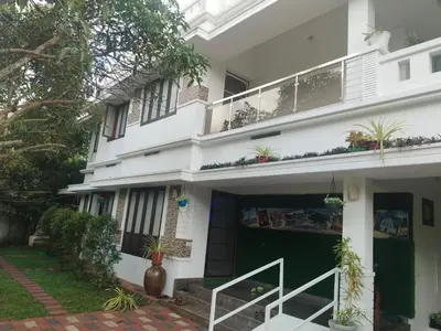a white house with a green door and a balcony at Willy's Home Stay in Parūr