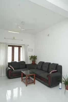a living room with a black couch and a table at Willy's Home Stay in Parūr