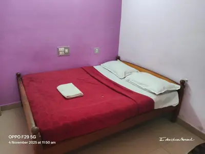a small bed with a red blanket on top of it at Hotel Srusti Residency in Mysore