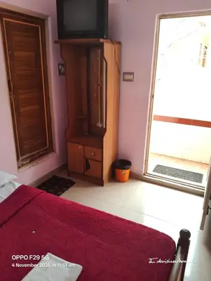 a bedroom with a bed and a tv and a window at Hotel Srusti Residency in Mysore