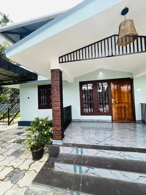 a white house with a brown door and a porch at Edakkal Hearth in Ambalavayal