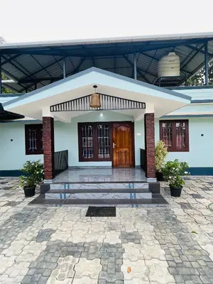 a white building with a wooden door and stairs at Edakkal Hearth in Ambalavayal