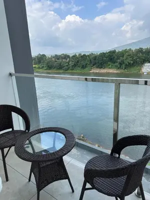 two chairs and a glass table on a balcony overlooking the water at Rivera resort and wellness center in Kodanad
