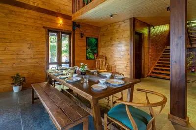 a wooden dining room with a wooden table and chairs at amã Stays & Trails - Iris Villa, Kozhikode in Puthuppādi