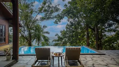 a patio with a table and chairs in front of a swimming pool at amã Stays & Trails - Iris Villa, Kozhikode in Puthuppādi
