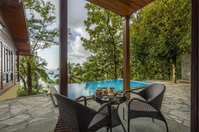 a patio with a table and chairs next to a swimming pool at amã Stays & Trails - Iris Villa, Kozhikode in Puthuppādi