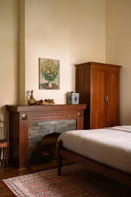 a bedroom with a fireplace and a bed and a wooden cabinet at amã Stays & Trails - Mount Pleasant, Coonoor in Coonoor