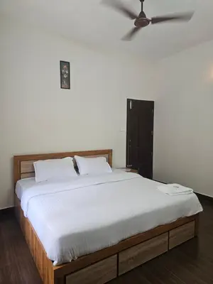 a bed with white sheets and a ceiling fan at Mount Wave Holiday Pool Villa in Wayanad