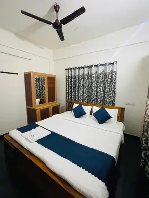 a bedroom with a large bed with a ceiling fan at Vythiri saara inn in Vythiri
