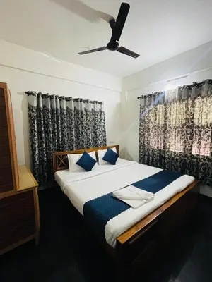 a bedroom with a bed with a ceiling fan at Vythiri saara inn in Vythiri