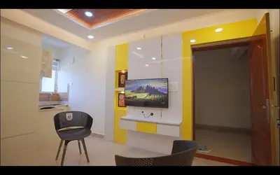 a room with a tv on a wall with a chair at Padmalaya Homestay ! in Guruvāyūr