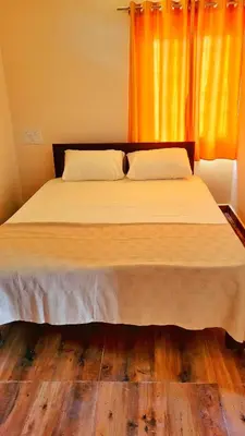 a bedroom with a large bed with an orange curtain at Eden Garden Bandipur Tiger Reserve in Gundlupet